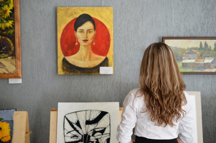 woman looking at piece of art on wall