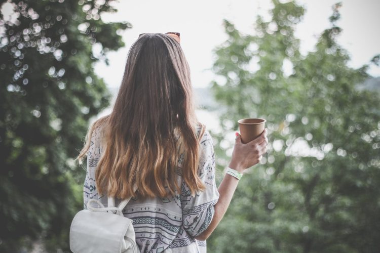 girl in gray with backpack holding a cup of coffee