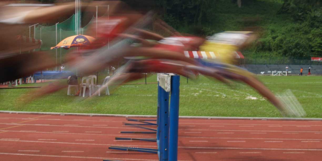 track runners hopping hurdles