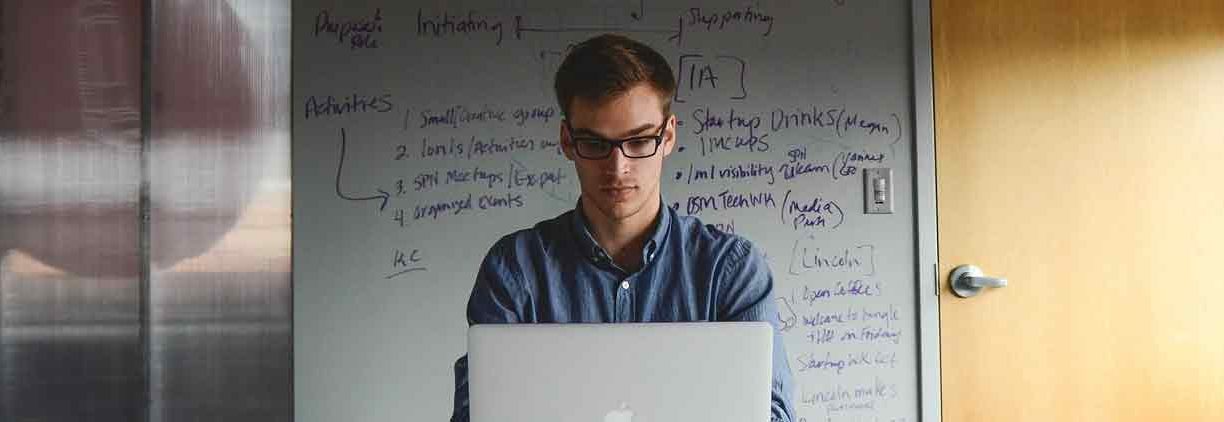man in glasses working on laptop