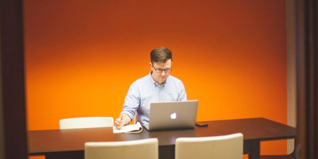 orange background man typing on laptop