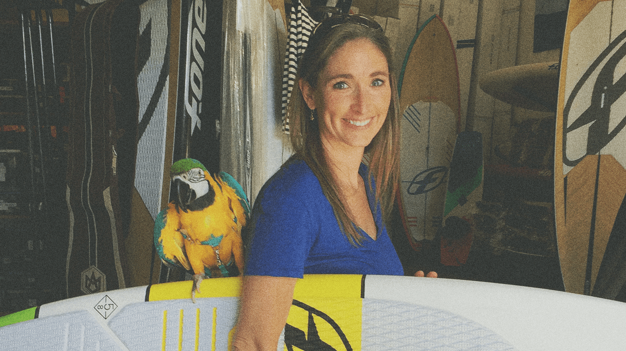 woman holding surfboard and parrot