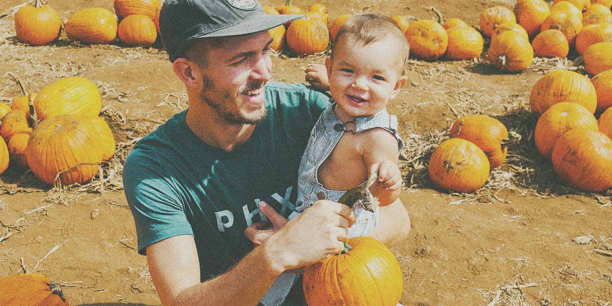 young man holding his baby in a pumpkin patch