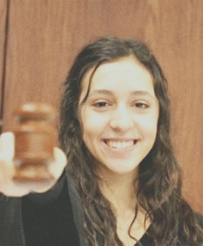 Photo of a young woman in a courthouse wearing a black robe and holding a gavel