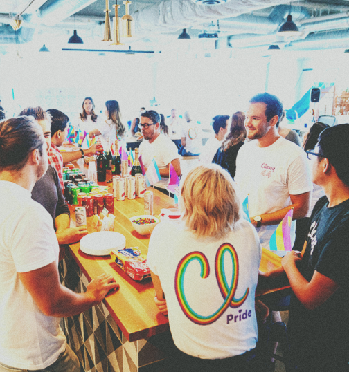 Photo of men and women in Classy tshirts interacting at a bar with food and drinks around them