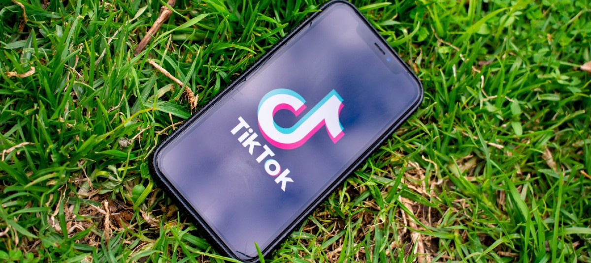 Phone lying in grass with TikTok displayed on the screen