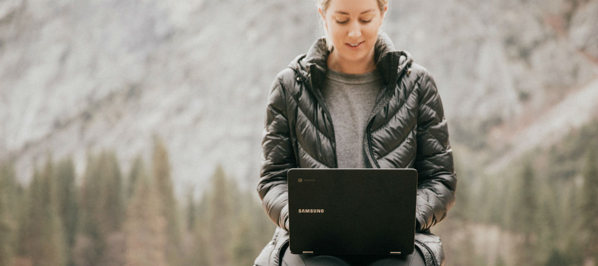 woman typing on laptop in nature