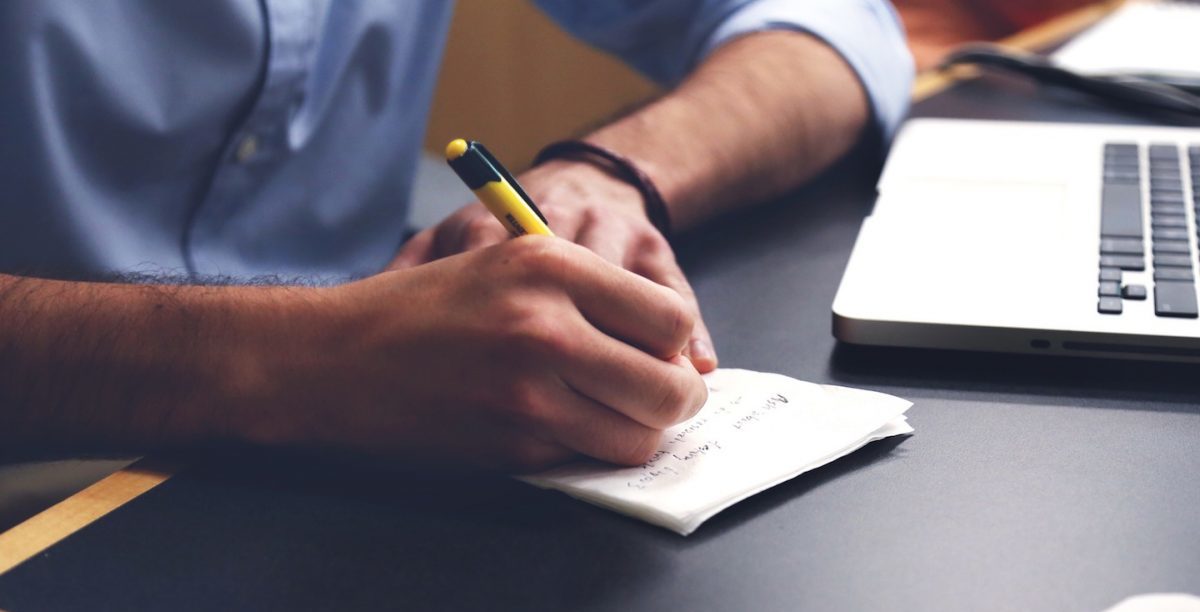 Man Writing Story in Notebook