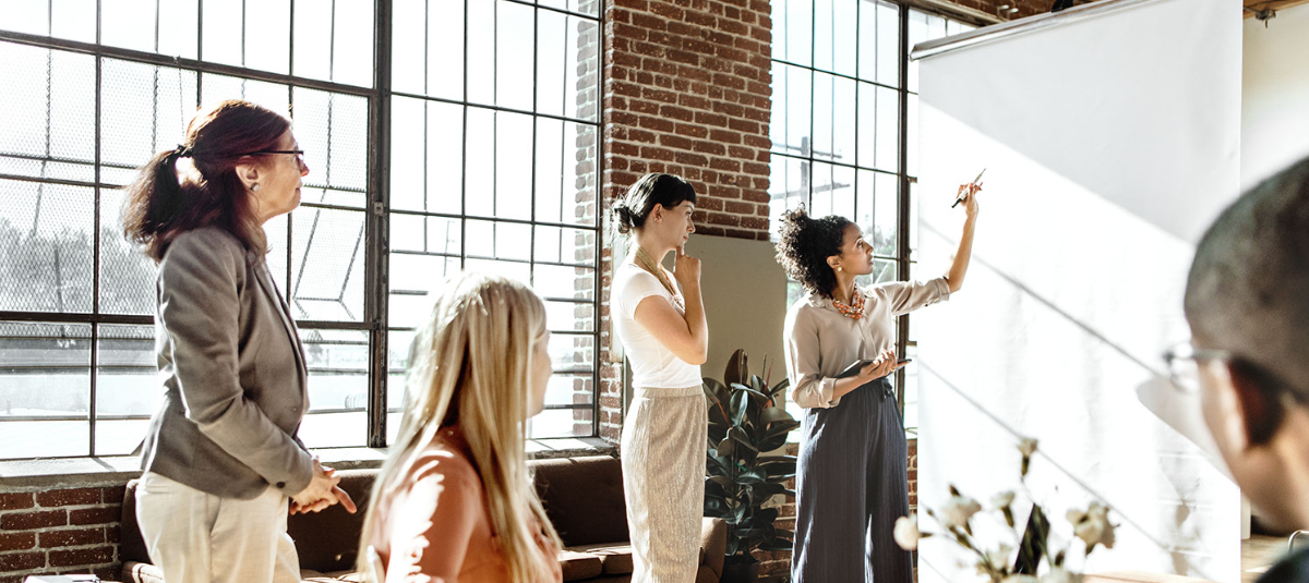 Employees working together with a white board in a brick office