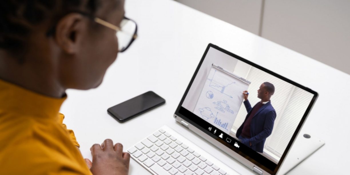 woman in gold watching a virtual webinar on her tablet