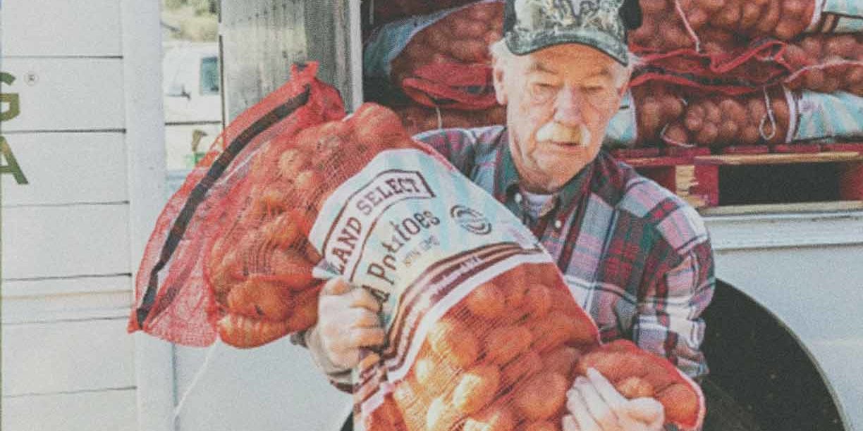 man in camo hat holding a bag of potatoes