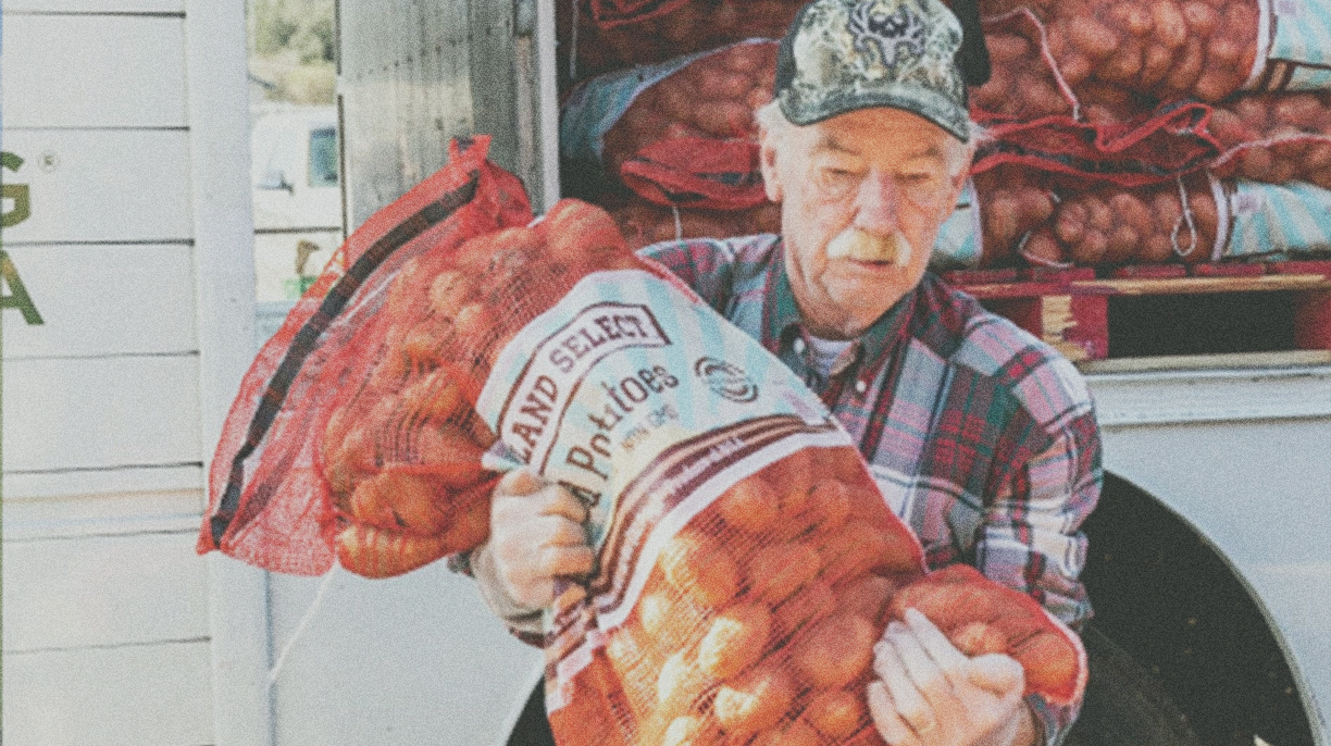 man in camo hat holding a bag of potatoes