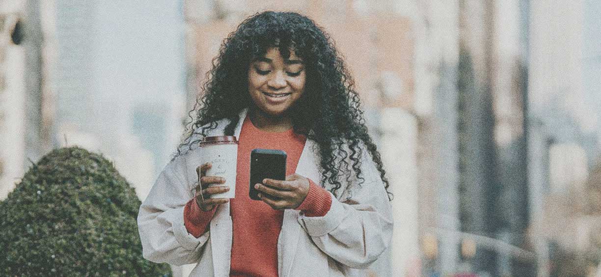 girl walking down the street texting holding coffee