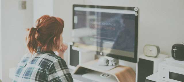 woman in plaid shirt working on desktop computer