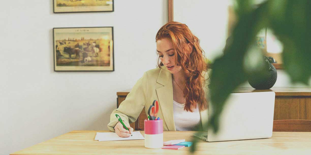 woman writing in notebook at desk