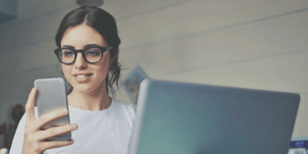 woman in white shirt and glasses looking at cell phone