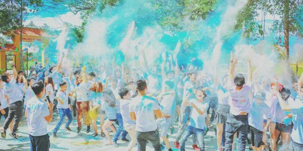 Young people throwing colored powder in the air at a fundraising event