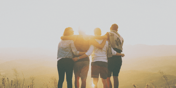 group hug in the mountains in front of sun