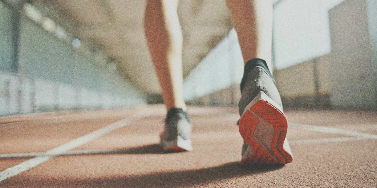 person in sneakers walking on a track