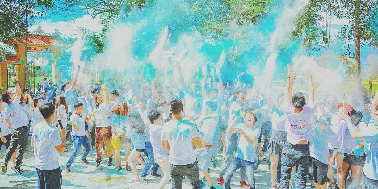 Group of young people throwing colored powder outside at a fundraising event