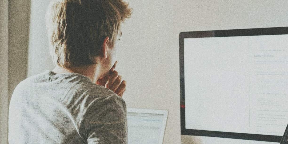 man in gray sitting at a computer