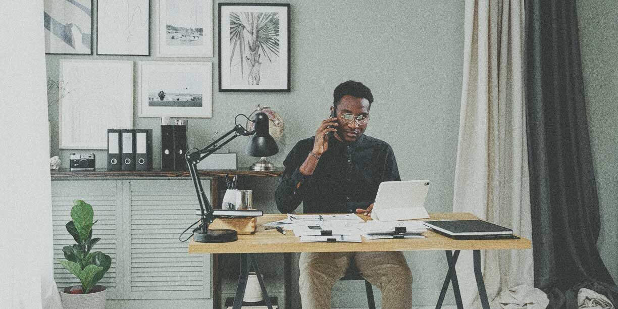 Man in black sitting in his home office working at a desk