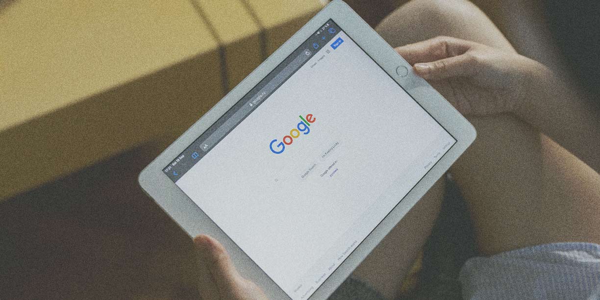 Person holding a tablet with Google's homepage displayed