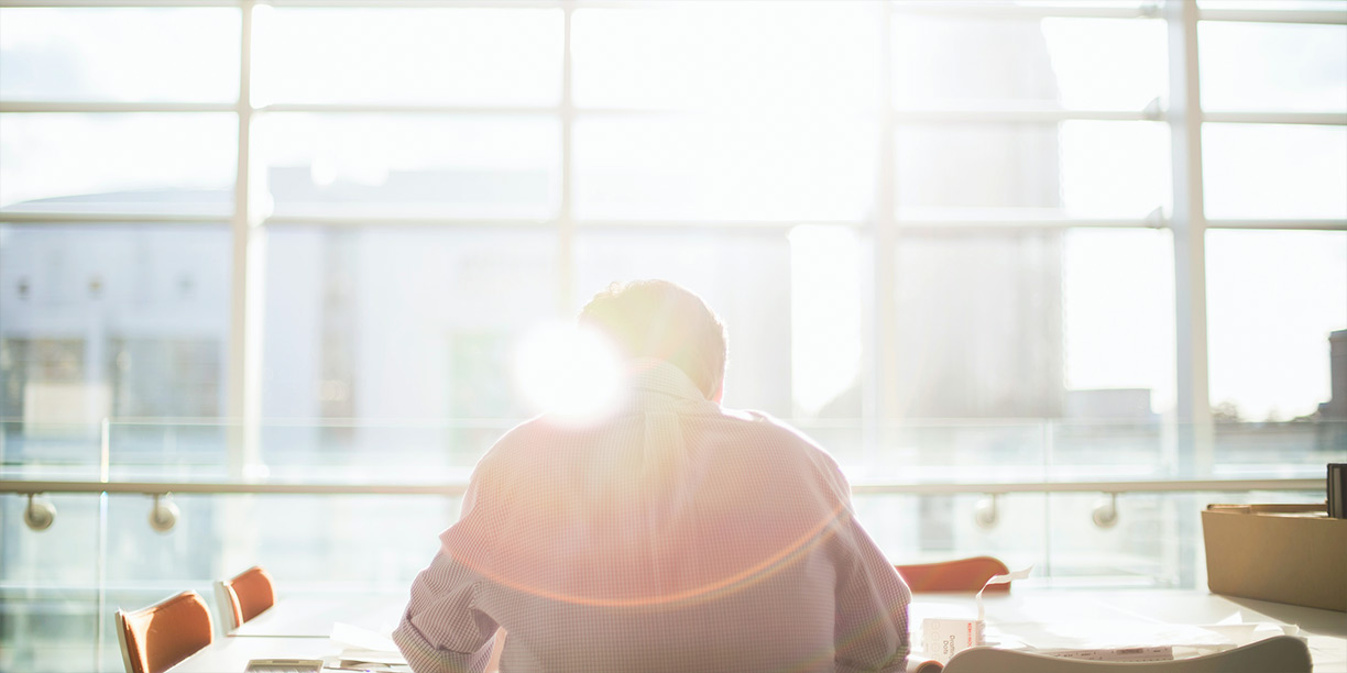 Person facing a bright window, sitting and working at a desk