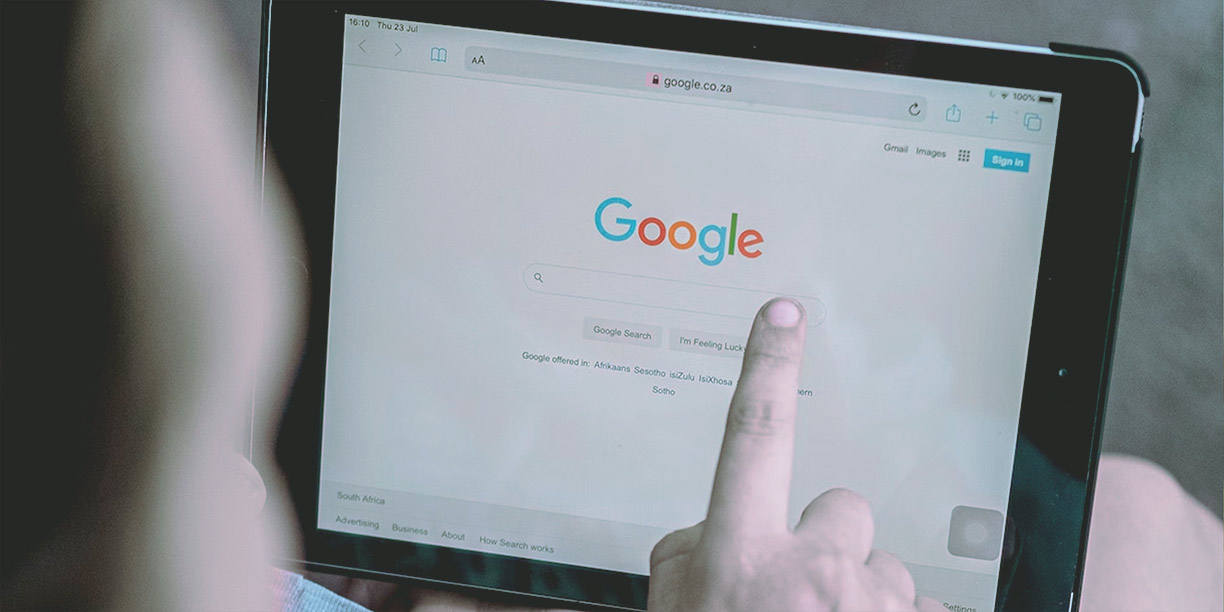 Person holding a tablet with Google's home screen displayed