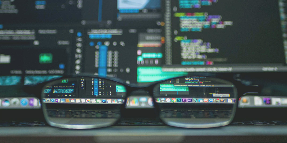 Computer screen displaying data with a pair of glasses sitting on the desk