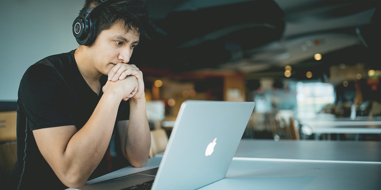 Man in black tshirt working on laptop in a coffee shop