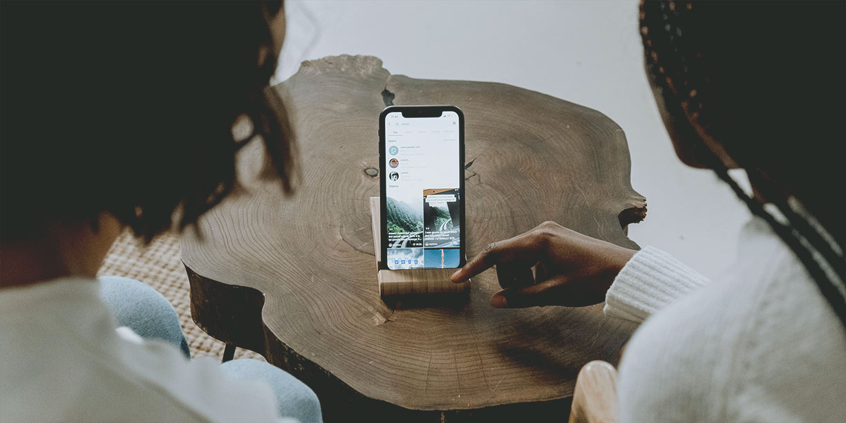 Two people scrolling through TikTok on a cell phone