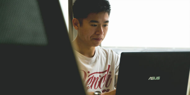 Man in white t-shirt performing data curation processes on laptop